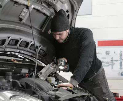 Homme qui réalise un entretien d'une voiture avec capot ouvert