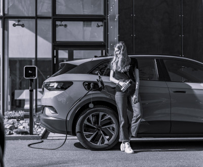 Photo en noir et blanc d'une femme qui recharge une voiture électrique