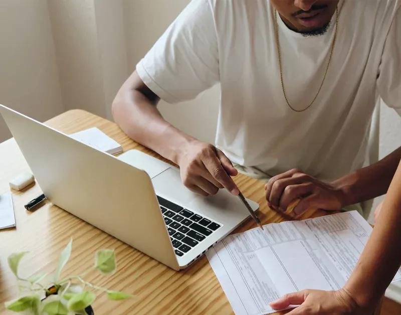 Un professionnel assis à son bureau, travaillant sur son ordinateur portable à propos du financement des voitures