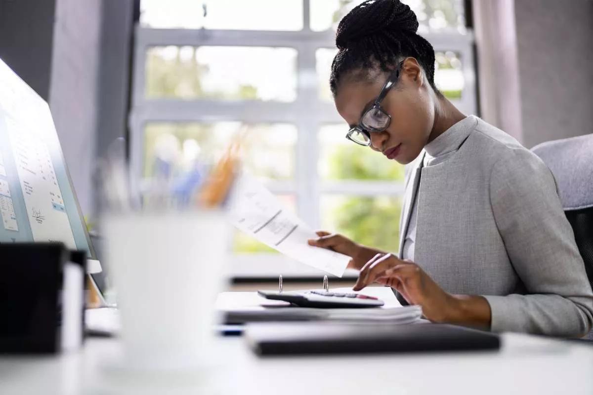 Femme comptable junior assise à un bureau en train de calculer les coûts de l'entreprise